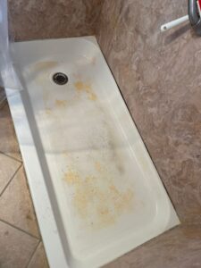 Shower floor before hard water stain removal – buildup and discoloration visible