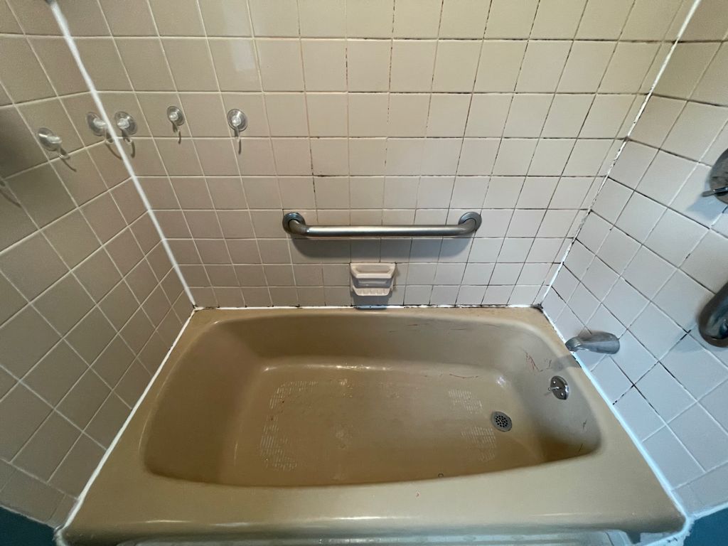 Bathtub and tiled shower walls before cleaning in Quincy, MA