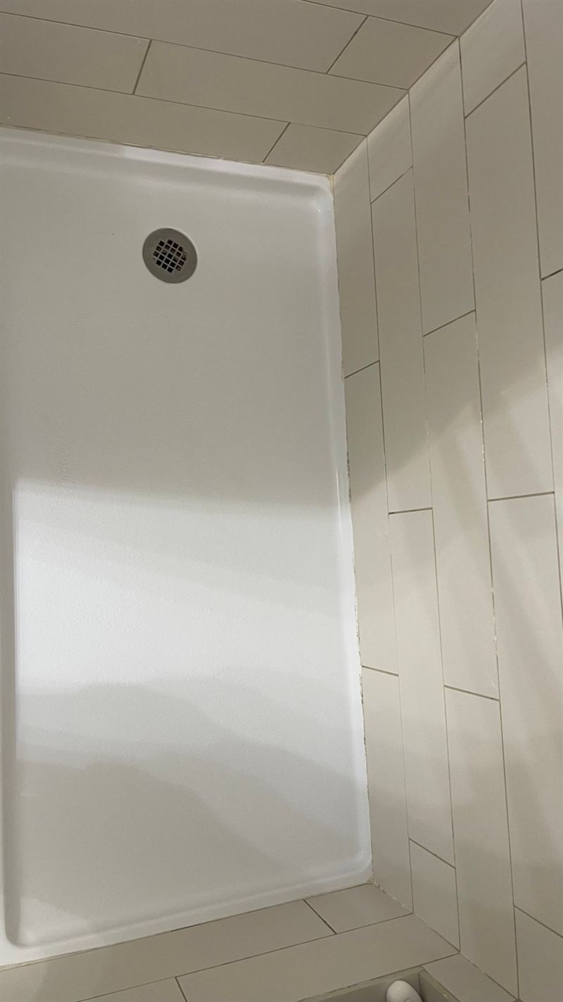 Shower base and white tile walls clean and bright after cleaning by Sirley Cleaning Services